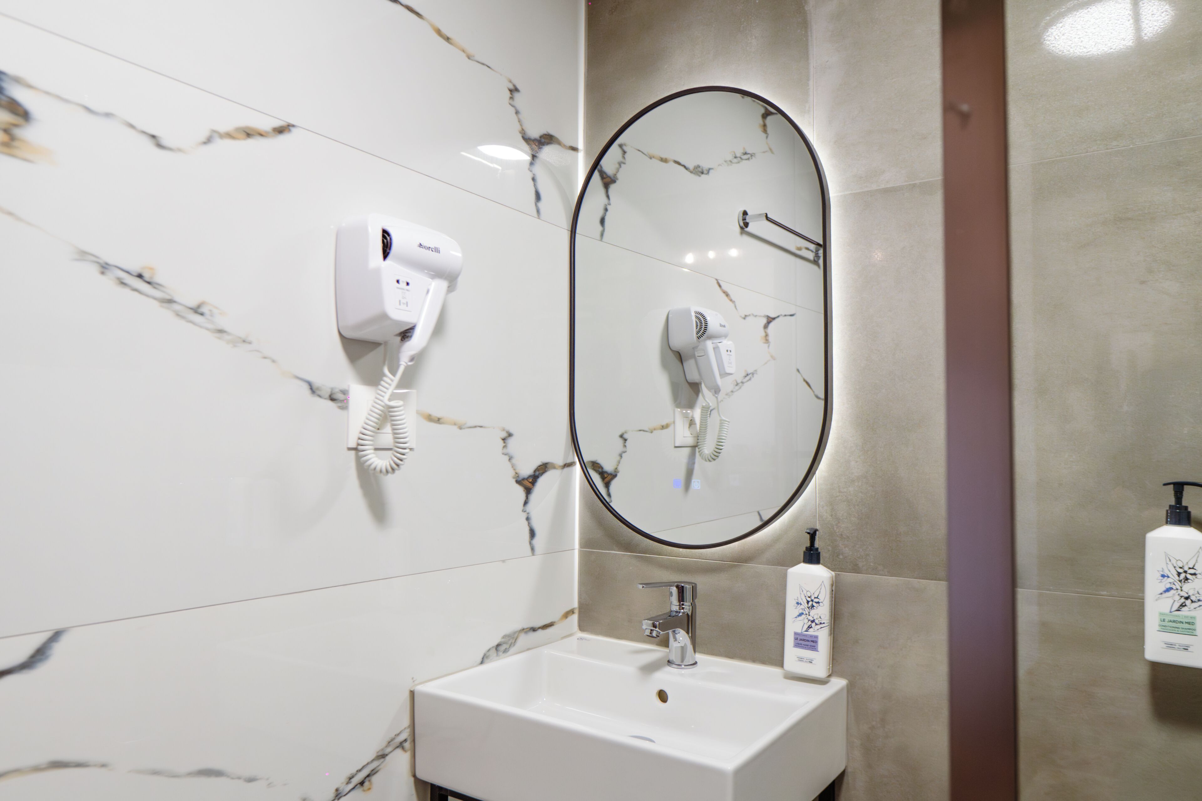 Un baño con lavamanos blanco, secador de pelo y espejo.
