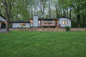 A modern two-story house with a stone retaining wall, a covered porch, and a well-maintained lawn. - Family friendly spacious 4 bed 3 BA house in West Asheville (Candler)