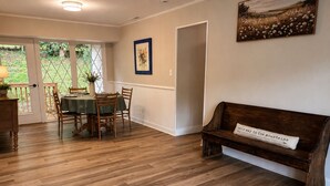 Un coin repas avec une table et des chaises en bois, un banc avec un coussin et un tableau accroché au mur.