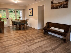 A dining area with a wooden table and chairs, a bench with a cushion, and a painting on the wall. - Family friendly spacious 4 bed 3 BA house in West Asheville (Candler)