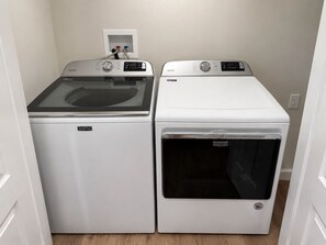 Two Maytag front-loading washing machines in a laundry room with a white wall and a power outlet. - Family friendly spacious 4 bed 3 BA house in West Asheville (Candler)