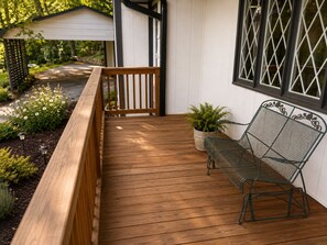 Una terraza de madera con un banco y una planta en maceta.