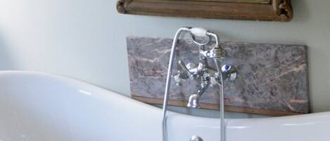 A bathroom with a freestanding bathtub, a wall-mounted mirror, and a marble tile backsplash.