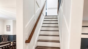 Una escalera de madera con paredes blancas que lleva a un piso superior.