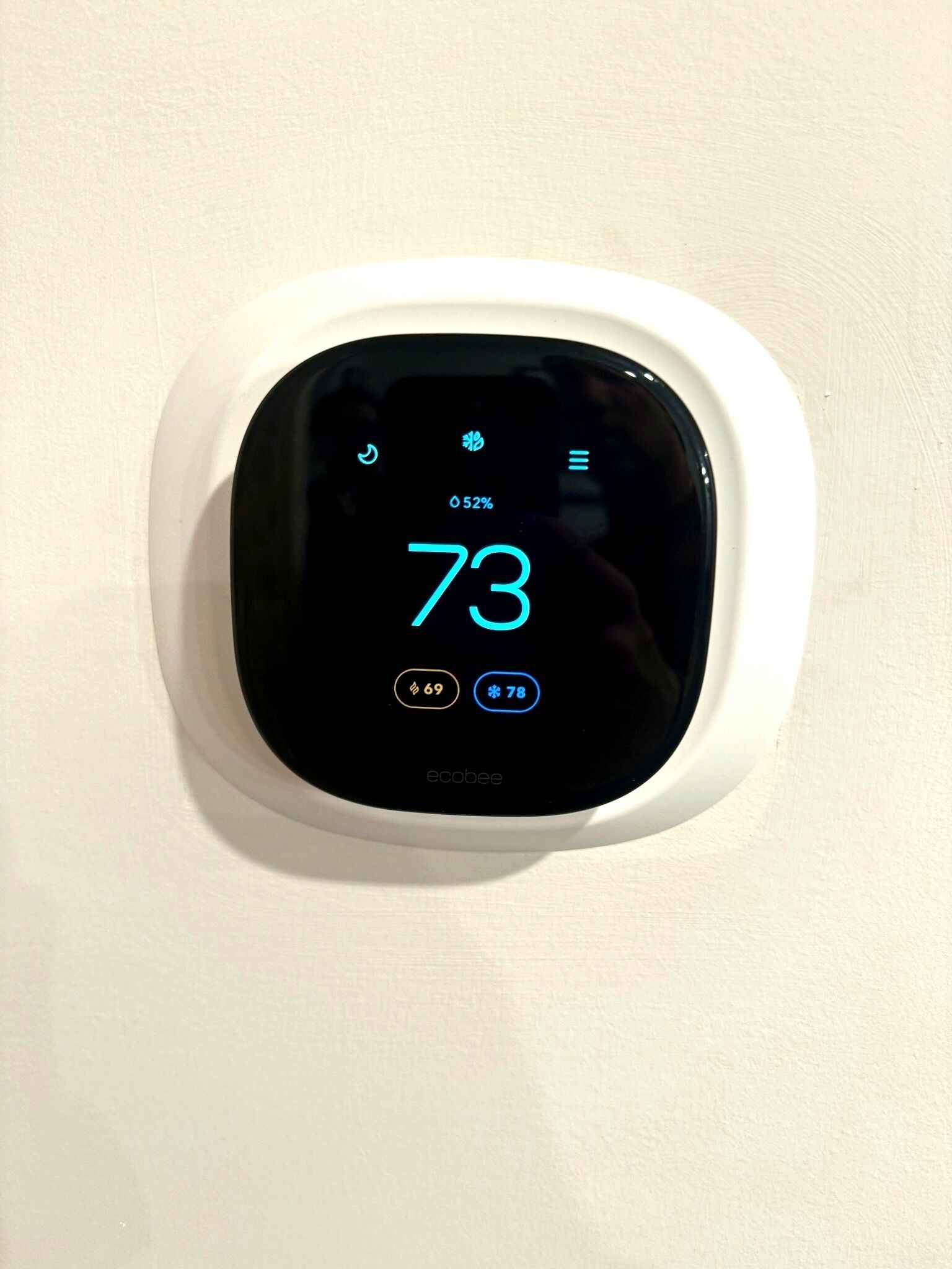 A thermostat with a digital display showing the temperature as 73 degrees.