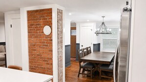 Una cocina moderna con una pared de ladrillo decorativa, una mesa de comedor de madera y una araña.