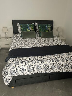 A bed with a patterned bedspread, two pillows with a peacock design, a dark headboard, and two bedside lamps. - Spacious 3-bedroom Villa in marvelous Cap-d'Ail with AC (Cap-d'Ail)