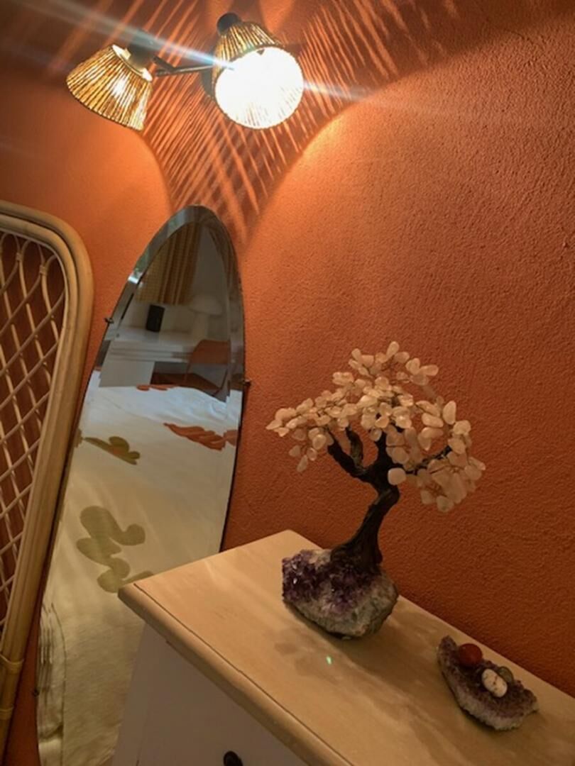 Une pièce avec un miroir, une petite sculpture d’arbre et un luminaire.