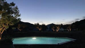 Una piscina rodeada de árboles y una casa al fondo.