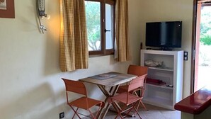 Una habitación pequeña con una mesa de comedor, sillas, un televisor y un sofá.