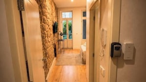 Ein Korridor mit einer Steinwand, Holzboden, einer Tür mit Telefon und einem Fenster zum Balkon.