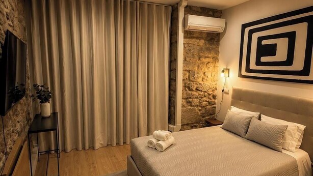 Ein Schlafzimmer mit Bett, Vorhängen, einer Wandklimaanlage, einem Blumentopf und einem Wanddekor.