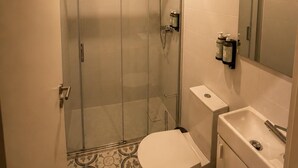 Ein Badezimmer mit Duschkabine, Toilette, Waschbecken und Spiegel.