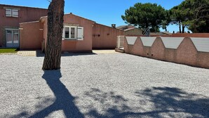 A building with a gravel driveway, a tree, and a wall with a geometric pattern. - 500 meters from the beach, a 3-bedroom family home with a terrace and barbecue (Agde)