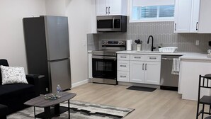 Eine moderne Küche mit weißen Schränken, einem schwarzen Kühlschrank und einer Mikrowelle.