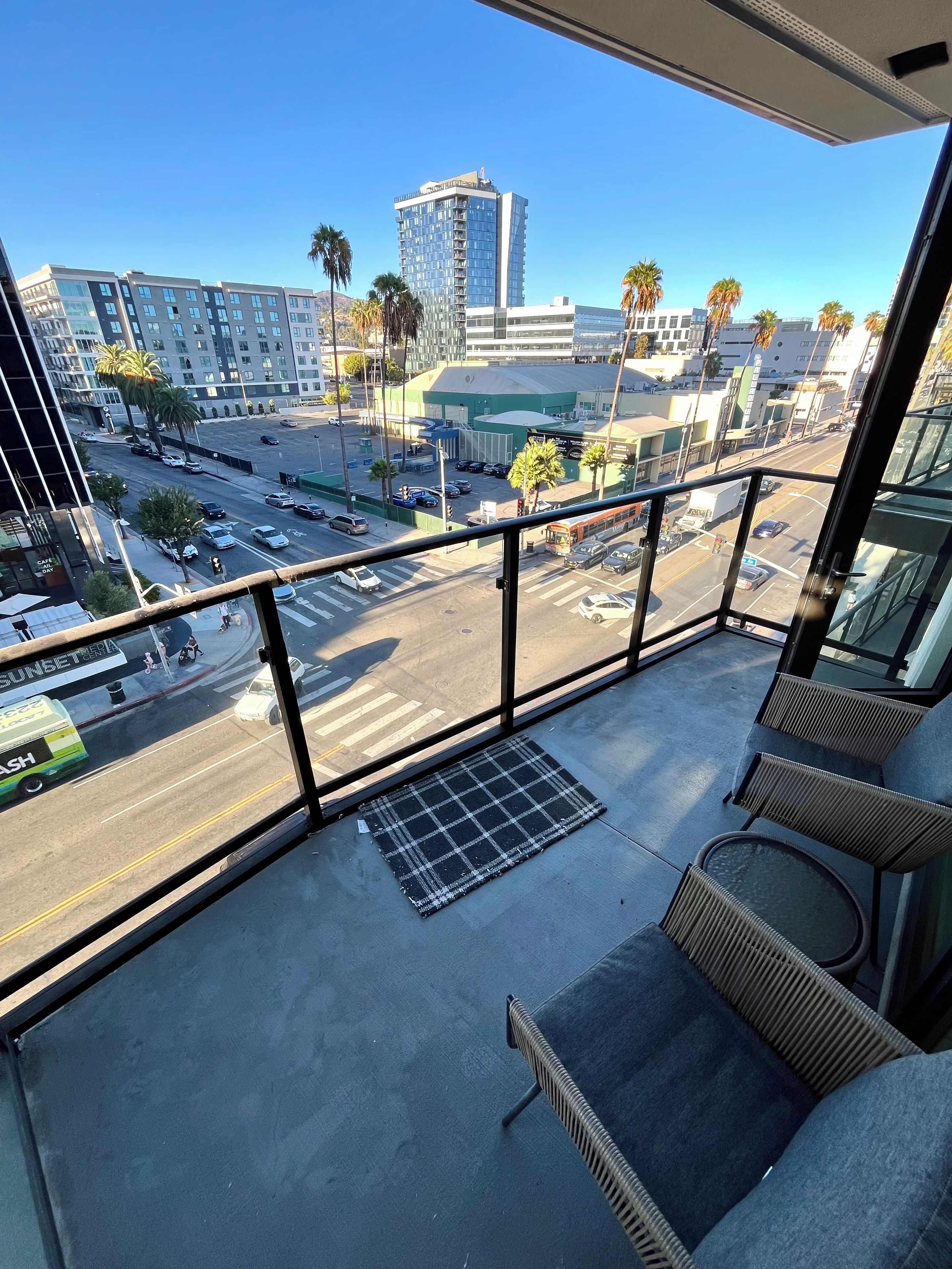 A balcony with a view of a cityscape, including buildings and palm trees.