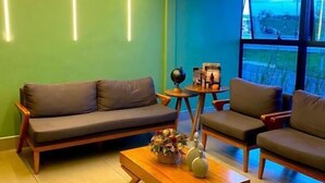 A modern living room with a sofa, armchairs, a coffee table, and a large window with a view. - Hotel Park (Valparaiso de Goias)