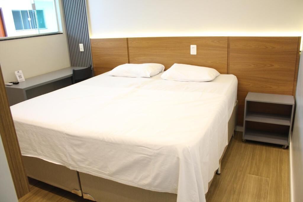 A single bed with a wooden headboard, a bedside table, and a small shelf unit.