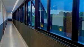 A corridor with large windows, a tiled floor, and a modern architectural design. - Hotel Park (Valparaiso de Goias)