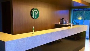 A reception desk with a logo, a counter, and a window with a view. - Hotel Park (Valparaiso de Goias)
