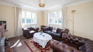 A room with a fireplace, a leather sofa, a round coffee table, and a large window. - Huge Peaceful 3Bed With FREE Parking (West Sussex)