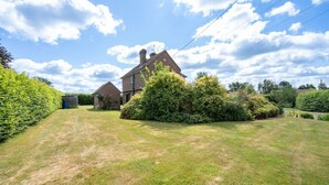 A residential property with a large lawn, a brick house, and a small shed. - Huge Peaceful 3Bed With FREE Parking (West Sussex)