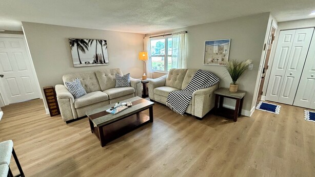 A living room with two sofas, a coffee table, and a lamp. - Fully Renovated Coastal Retreat 3BR w/ Garage & Screened Lanai (Apollo Beach)
