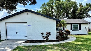 A single-story house with a garage, a number sign, and a well-maintained lawn. - Fully Renovated Coastal Retreat 3BR w/ Garage & Screened Lanai (Apollo Beach)