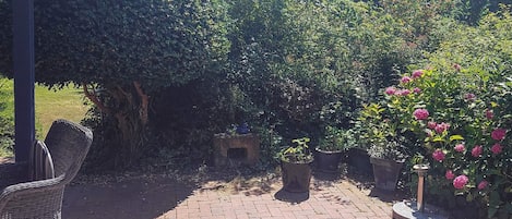 A brick patio with potted plants and a wicker chair.