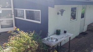 A small, single-story building with a dark exterior, a white door, and a window. - 4 Star Holiday Home in Hundested (Hundested)