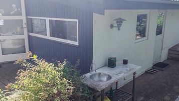 En lille, etagebygning med mørkt ydre, en hvid dør og et vindue.