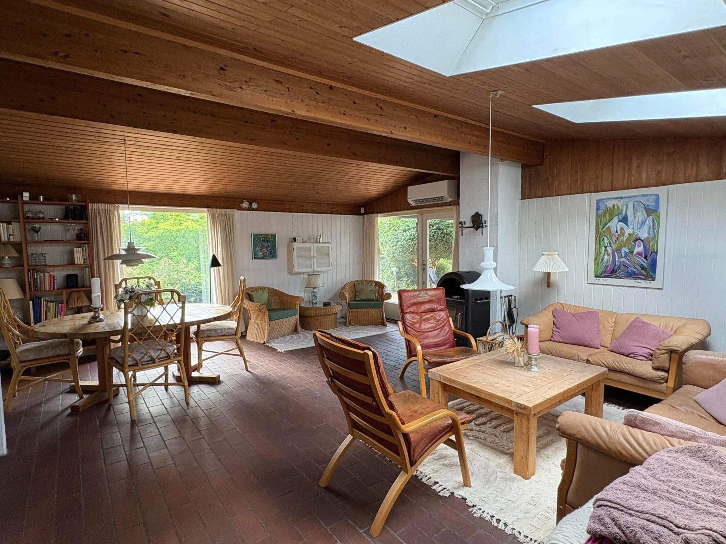 A cozy living room with wooden furniture, a fireplace, and a large window.