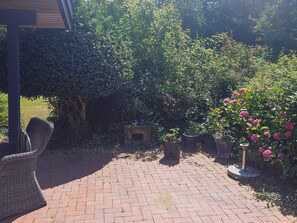 A paved patio area with potted plants and a wicker chair. - 4 Star Holiday Home in Hundested (Hundested)