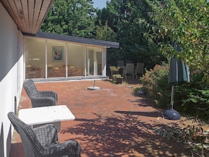 A patio with wicker furniture, a table, and chairs.