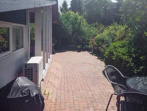 A patio area with a brick floor, a covered grill, and outdoor furniture. - 4 Star Holiday Home in Hundested (Hundested)