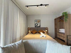 A modern bedroom with a bed, bedside lamps, a headboard, a wardrobe, and a hanging plant. - Vrbo Property (São Paulo)