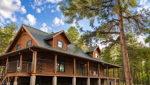 A log cabin with a porch, multiple windows, and a covered deck area.