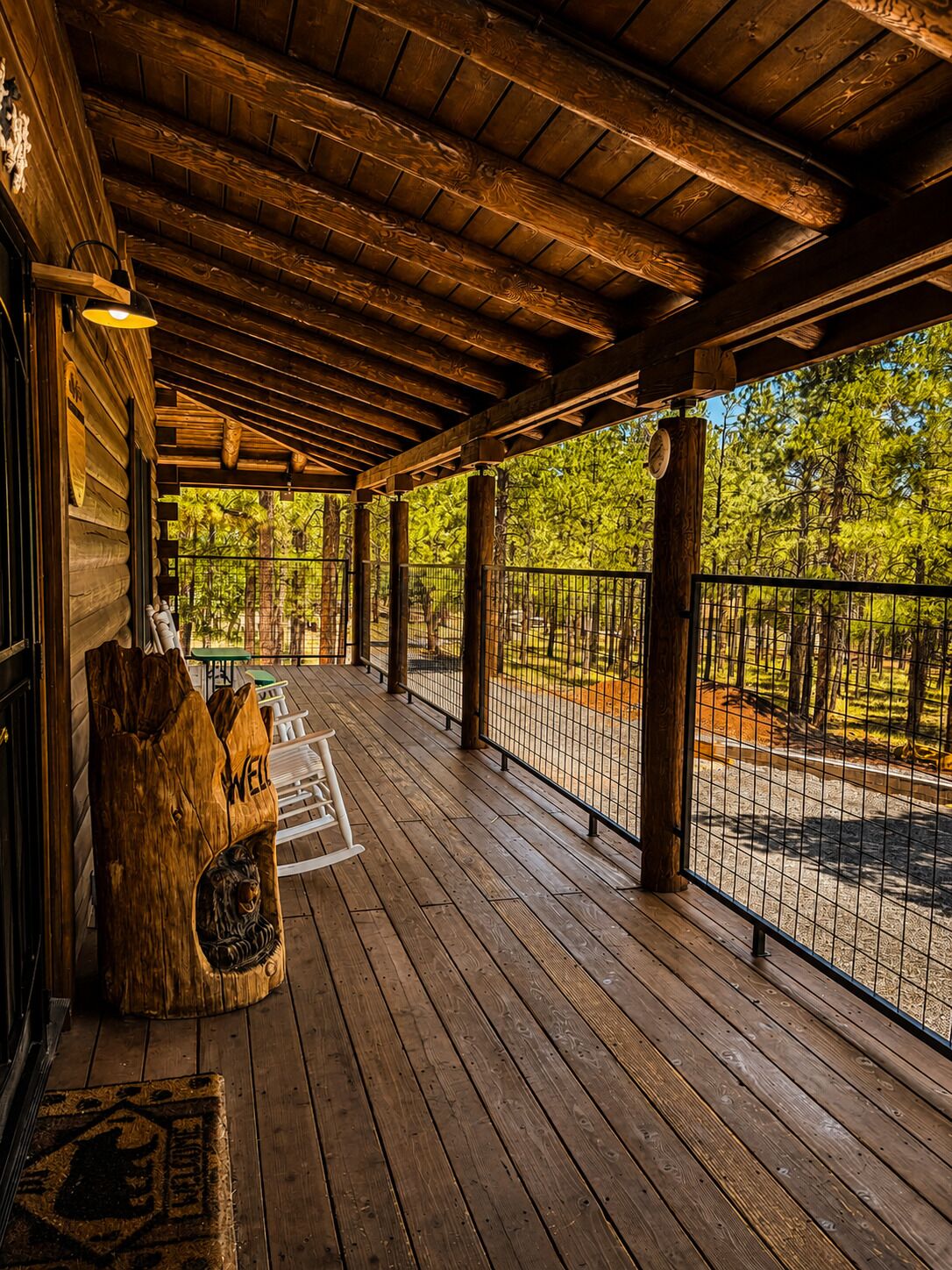 A wooden deck with a railing, a wooden post with a lion carving, and a bench.