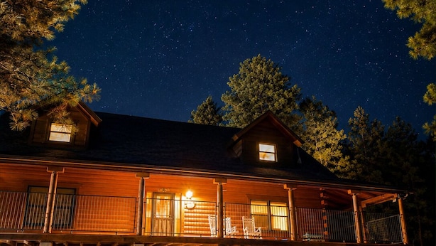 A lodge with a fire pit, outdoor seating, and a starry night sky.