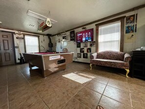 Ein Zimmer mit Billardtisch, einer Couch und einem Fernseher, der eine Speisekarte zeigt.