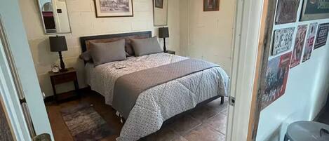 Ein Schlafzimmer mit einem Bett, einem Nachttisch, einer Lampe und einem Deckenventilator.
