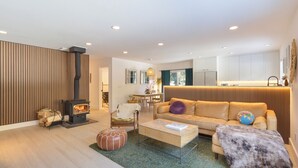 A modern living room with a fireplace, sofa, coffee table, and a dining area. - Mountain Modern Retreat with Saltwater Hot tub and Cedar Sauna (Truckee)