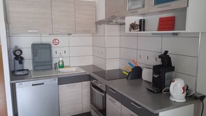 Een functionele keuken met vaatwasser, broodrooster, waterkoker en koffiezetapparaat.