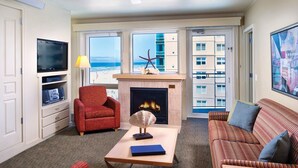 Una sala de estar con chimenea, televisión y vistas a la playa.