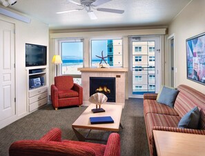 Una sala de estar con chimenea, televisión y vistas a la playa.