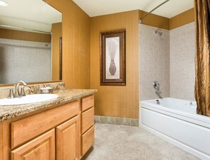 A bathroom with a sink, vanity, bathtub, shower, and a framed picture on the wall. - Seaside!! Condo with view, Balcony, Grill, just steps to the beach! (Seaside)