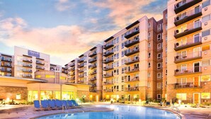 Un hotel de varios pisos con piscina, zona de estar exterior y balcones.