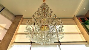 Un candelabro grande y ornamentado cuelga del techo en una habitación espaciosa con ventanas amplias y una paleta de colores neutros.