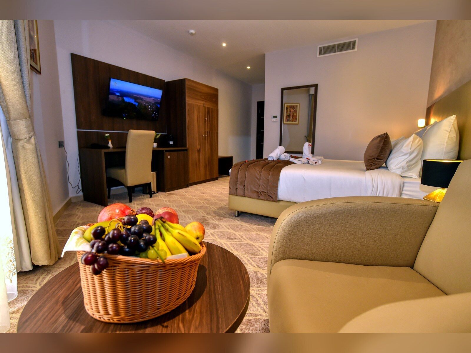 Une chambre d’hôtel équipée d’un lit, d’une télévision, d’un bureau et d’un panier de fruits.