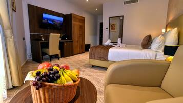 Une chambre d’hôtel équipée d’un lit, d’une télévision, d’un bureau et d’un panier de fruits.